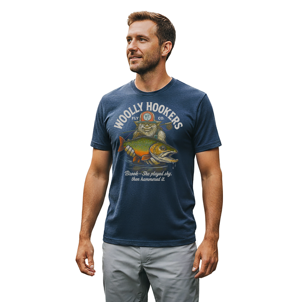 Man fly fishing wearing Woolly Hookers “Brook Played Shy” tee on the river at sunset.
